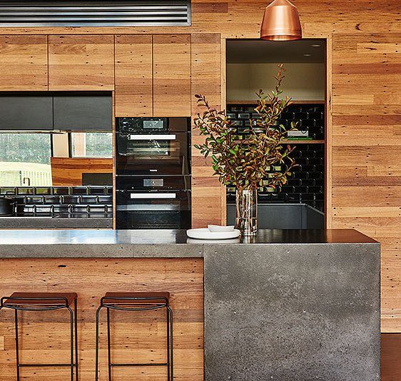 Cocina con frente de madera e isla de hormigón